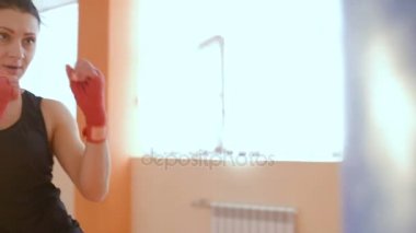 Kız spor giyim ve kırmızı boks bandaj spor salonunda boks armut yener