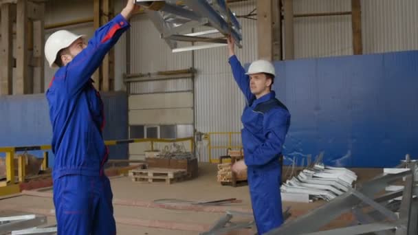 Arbeiter im Werk laden die Ladung vor dem Hintergrund der Produktion auf den Haken des Krans — Stockvideo