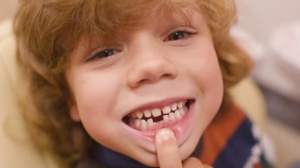 Een kleine jongen met krullend haar in een tandheelkundige stoel — Stockvideo