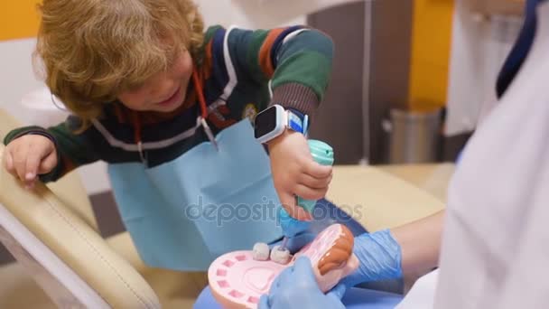 Un niño pequeño juega con un dentista en un dentista herramientas de juguete . — Vídeo de stock