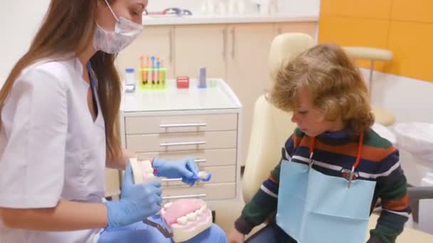 De tandarts vertelt het kind over mondhygiëne — Stockvideo