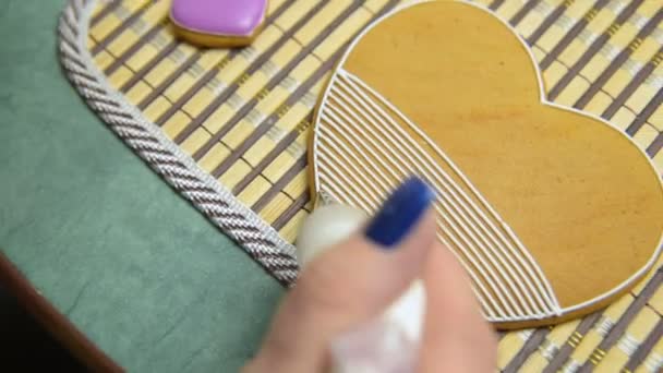 Woman confectioner decorates and decorates the glaze with gingerbread cookies in the shape of heart. — Stock Video