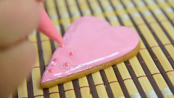 Vrouw banketbakker siert en siert het glazuur met gingerbread koekjes in de vorm van hart. — Stockvideo