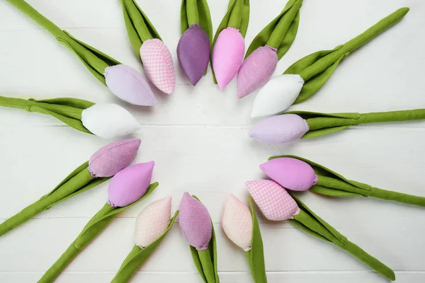 Tulipanes de juguete dispuestos en un círculo sobre un fondo de madera blanca . — Foto de Stock