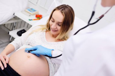 doctor gynecologist examines a pregnant woman with a large belly clipart