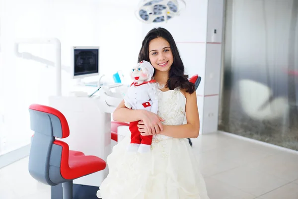 A kislány egy baba, a háttérben a klinika — Stock Fotó