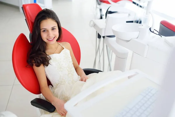 Aranyos kislány, mosolygós, piros fogászati szék — Stock Fotó