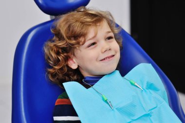 curly-haired baby in blue dental chair