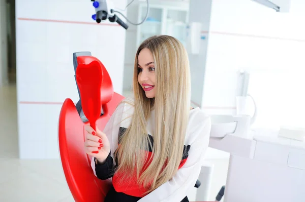 Красивая молодая девушка в красном стоматологическом кресле — стоковое фото