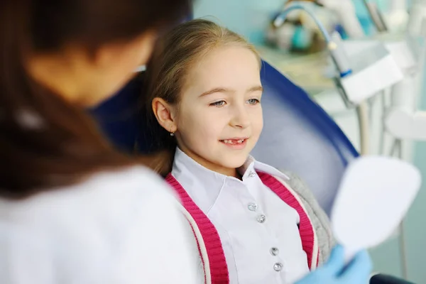 Bebê menina examina dentes em um espelho dental — Fotografia de Stock