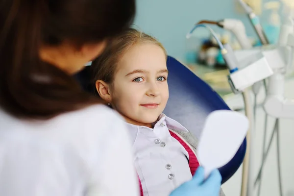Menina examina dentes em um espelho dental — Fotografia de Stock