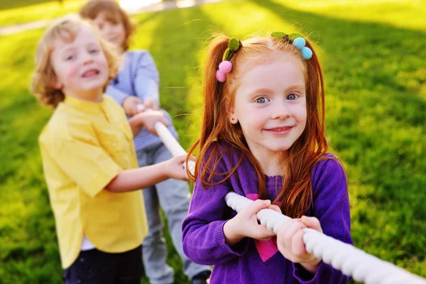 Barnen leka dragkamp i parken. — Stockfoto