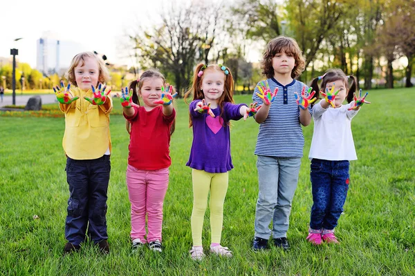 Um grupo de crianças pequenas com as mãos sujas na pintura a cores jogar no parque . — Fotografia de Stock