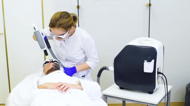 Jovem sobre o procedimento de descascamento de carbono no fundo da sala de cosmetologia moderna. Cosmetologia a laser — Vídeo de Stock