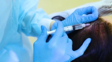 cosmetic surgery performs a procedure for hair regeneration by mesotherapy-injection of the patients plasma into the scalp.