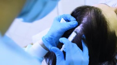 cosmetic surgery performs a procedure for hair regeneration by mesotherapy-injection of the patients plasma into the scalp.