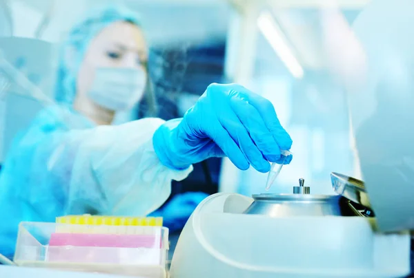 Científica femenina en una máscara médica protectora y guantes de goma hace pruebas de ADN PCR en un laboratorio químico y bacteriológico moderno . — Foto de Stock