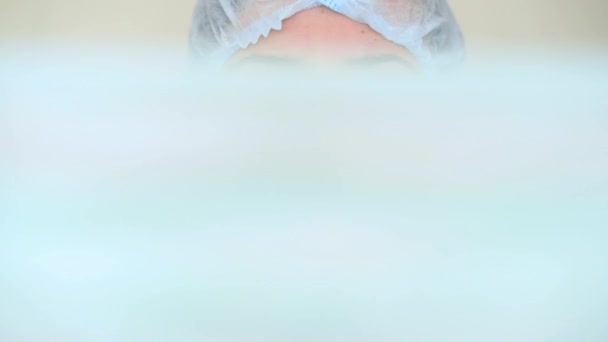 Young female doctor or nurse puts on a medical protective mask on a white background. Coronavirus, epidemic, pandemic, covid-19 — Stock Video