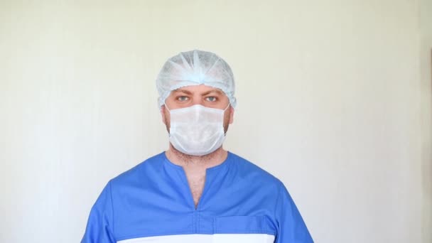 Médico ginecólogo loco muecas en un vestido médico, guantes de goma, y un sombrero desechable . — Vídeos de Stock