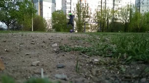 Enfant un garçon d'âge préscolaire frappe un ballon de football et est frappé par une caméra vidéo qui tombe de l'impact — Video