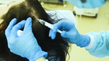 cosmetic surgery performs a procedure for hair regeneration by mesotherapy-injection of the patients plasma into the scalp.