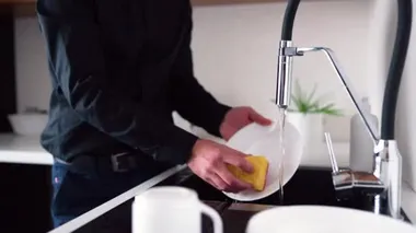 Lavaboda durup bulaşık yıkamak için musluğu açan adamı görüyor musun? Yemekten ya da öğle yemeğinden sonra temiz beyaz tabaklar. Yıkandıktan sonra musluk kapanıyor.