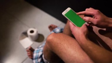 Pantolon giymiş bir adamın elinde telefonu açıp kullanmaya başlamasının videosu. Yukarı, aşağı ve kaldırma da resimlerde yakınlaştırma.