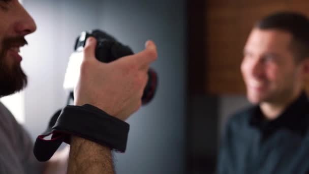 Process of changing camera focus. Blurred front part or background. Cameraman talking pictures or shooting video of businessman in black shirt talking and smiling. — Stock Video