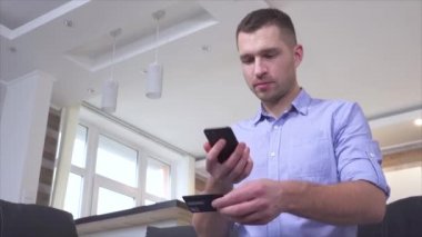 Çevrimiçi ödeme için kredi kartı numarasını tarayan genç adam. Karttan akıllı telefon hesabına para yollamak. Mutlu olumlu adam işlemden memnun..