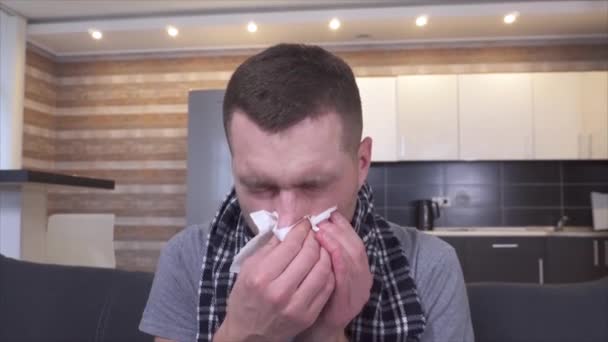 A beteg fiatalember torokgyulladásban és betegségben szenved. Tüsszentés fehér szalvétába és orrspray használata. Fejfájás és rossz érzés. Beteg fickó a konyhában.. — Stock videók