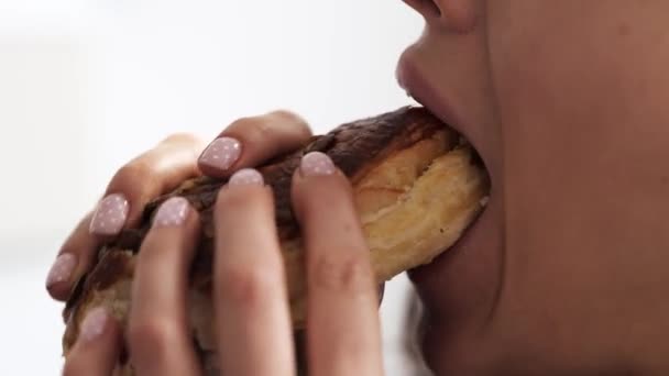 Una joven se queda en casa durante la cuarentena. Cerrar y cortar vista aislada sobre fondo blanco. Chica mordiendo gran pedazo de hamburguesa o bollo sabroso. Masticar deliciosa comida gorda. Movimiento lento . — Vídeos de Stock