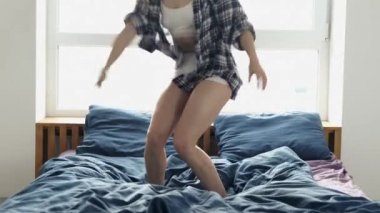 Genç kadın karantina sırasında evde kalıyor. İnce yapılı, pijama giymiş bir kız ya da yatakta zıplayıp duran bir ev elbisesi. Yalnız iyi eğlenceler. Yavaş çekim.