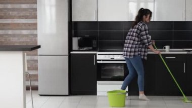 Karantina sırasında mutfakta genç bir kadın. Yerleri paspas ve dansla silmek. Temizlik sırasında şarkı söylemek. Dairesinde iyi vakit geçirsin..