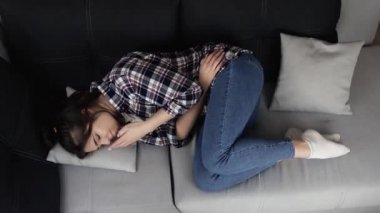 Karantina sırasında mutfakta genç bir kadın. Kanepede yatan ve karın ağrısı çeken bir kız. Adet dönemi ya da kabızlık. Bununla başa çıkamam..
