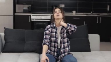 Karantina sırasında mutfakta genç bir kadın. Boynu ağrıyan bir kız kanepeye oturur ve cildine masaj yapar. Acıdan muzdarip. Yorucu bir ağrı..