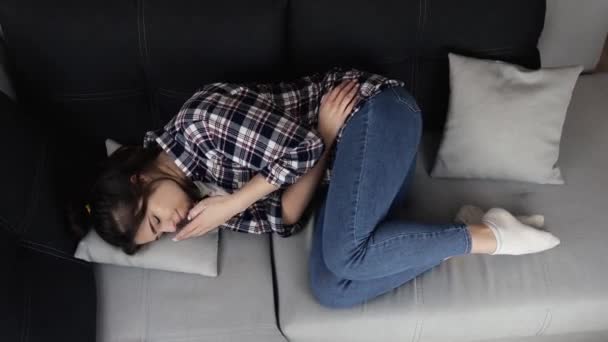 Young woman in kitchen during quarantine. Girl lying on sofa and suffer from stomach pain and ache. Menstrual period or constipation. Cant handle with it. — Stock Video