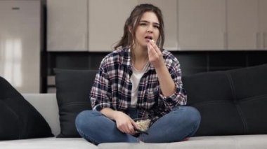 Karantina sırasında mutfakta genç bir kadın. Bacak bacak üstüne atmış bir şekilde kanepeye otur ve film izle. Patlamış mısır ye ve düz bak. Film izlerken tartışmalar.