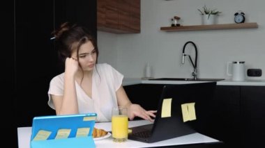 Karantina sırasında mutfakta genç bir kadın. Evden kumandayla çalışıyor ve dizüstü bilgisayar kullanıyor. Neşeli olmaya başla, mutlu ol ve çığlık at..