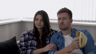 Karantina sırasında mutfakta genç bir çift. Kanepede birlikte oturup televizyon ya da film izleriz. Adam muz yiyor. Etrafı çöpleri geri dönüşümle çevrili. Kamera geri gidiyor.