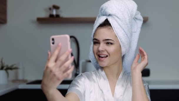 Mujer joven en la cocina durante la cuarentena. Use ropa de baño después de la ducha o el spa. Tomando selfie o foto. Obtener placer de mirarse a sí misma . — Vídeos de Stock