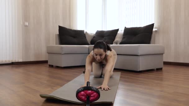 Ung kvinna har träning hemma under karantänen. Kvinna som sträcker sig framåt på yogamattan alltifrån att sitta poserar. Vidrör golvet med bröstet och böj ryggen med blicken framåt. — Stockvideo