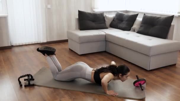 Jonge vrouw heeft thuis training tijdens quarantaine. Intensieve push-ups zonder apparatuur. Ga op je knieën staan en train. Handen sterker maken. — Stockvideo