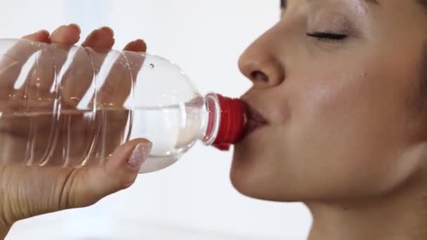 Mladá žena má doma během karantény cvičení. Detailní záběr štíhlé fit dívka pitné vody po tréninku. Užívání hydratace. — Stock video