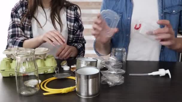 Young couple in kitchen during quarantine. Close up of people sorting trash and renewable garbage together. Care about environment. — Stock Video