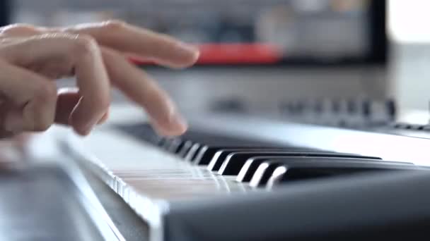 在录音室里的年轻人用右手在钢琴键盘上弹奏手的特写.学习如何使用电子合成器。学生. — 图库视频影像