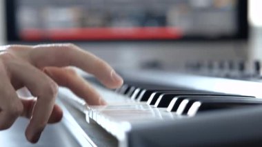 Ses kayıt stüdyosundaki genç adam. Sağ elin leyboardda oynadığı ağır çekimde. Profesyonel olmayan erkek öğreniyor ya da öğreniyor.
