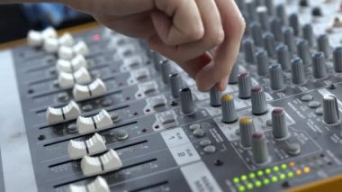 Ses kayıt stüdyosundaki genç adam. Yaklaş ve yavaş çekimde görüntüyü kes. Müzik konsolu ekipmanlarıyla çalışmak.