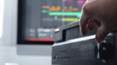 Ses kayıt stüdyosundaki genç adam. Sağ el değiştiren adamların yavaş çekim videosunu kapat. Ses karıştırma konsolu dokunuyor.