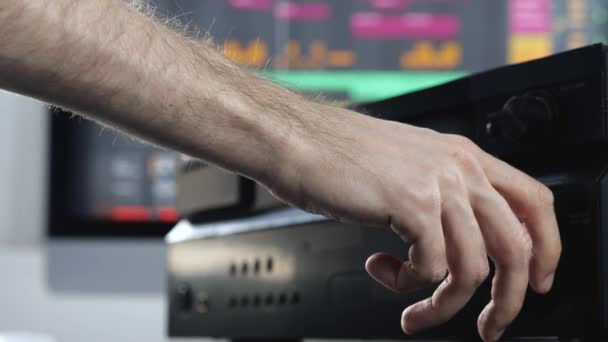 Joven en el estudio de grabación de sonido. Movimiento lento de la mano que alcanza la música consol. Cambiando de volumen. Primer vídeo . — Vídeo de stock