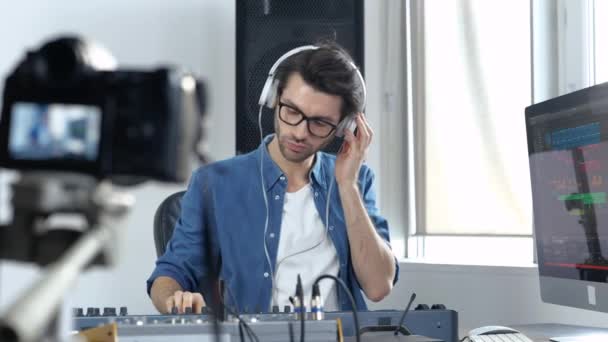 Mladý muž v nahrávacím studiu. Guy natáčení procesu práce s hudbou mixování konzole a poslech to přes sluchátka. Zpomalený pohyb. — Stock video